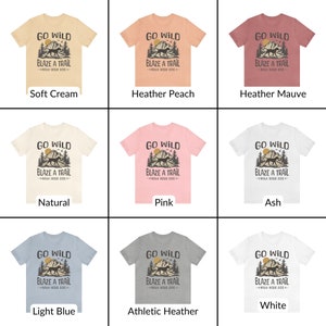 May include: A collage of nine t-shirts in different colors, each featuring a graphic design of a dog running through a mountain landscape with the text "Go Wild Blaze a Trail With Your Dog". The t-shirts are displayed on a white background.
