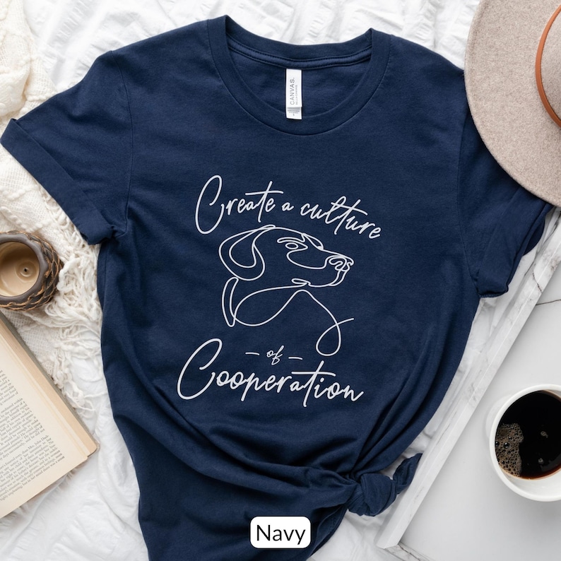 May include: Navy blue t-shirt with a white outline of a dog's head and the text "Create a culture of Cooperation".