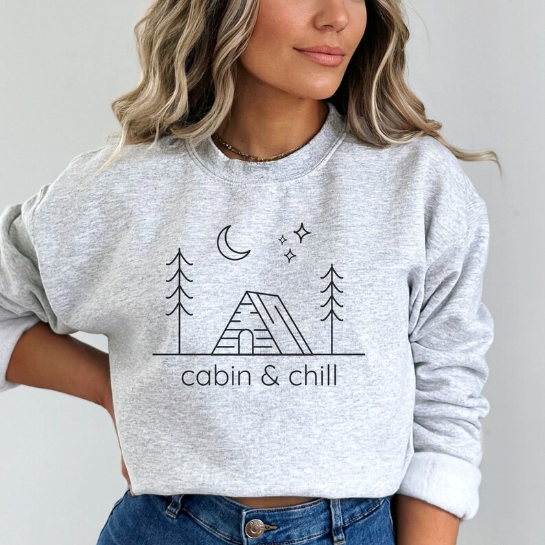 May include: Gray sweatshirt with a black line drawing of a cabin, trees, a moon, and stars. The text "cabin & chill" is below the drawing.