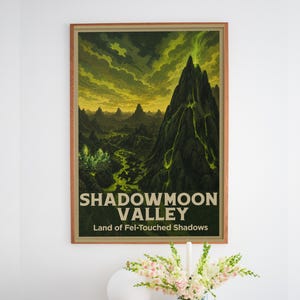 May include: A framed rectangular wall art print featuring a dark, mountainous landscape with glowing green lava flows and a yellow sky. The text reads SHADOWMOON VALLEY and Land of Fel-Touched Shadows in a bold, light-colored sans-serif font.