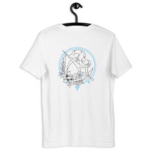 May include: White t-shirt with a blue and black design on the back. The design features a stylised woman holding a sword, surrounded by flowers and stars.
