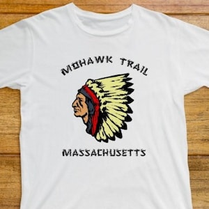 May include: White t-shirt featuring a graphic of a Native American wearing a headdress. The text "MOHAWK TRAIL MASSACHUSETTS" is printed below the graphic.