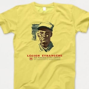 以下が含まれることがあります： 軍服を着た男性のヴィンテージスタイルのグラフィックがプリントされた黄色のTシャツ。グラフィックには「Légion Étrangère」と「Ses Marches et Ses Chants」のテキストが含まれています。