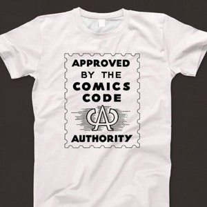 Peut inclure: T-shirt blanc avec un graphique noir et blanc d'un timbre qui dit "APPROVED BY THE COMICS CODE AUTHORITY" avec un "CA" stylisé à l'intérieur.