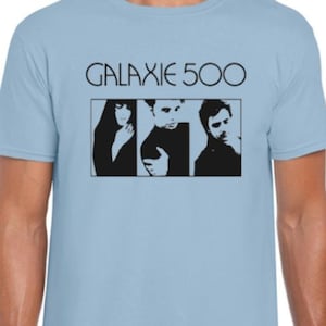 May include: Pale blue t-shirt with the text "GALAXIE 500" above a black and white image of three people. The shirt has a crew neck and short sleeves.