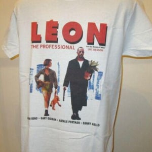 Könnte beinhalten: Weißes T-Shirt mit dem Filmtitel "LEON" in roten Blockbuchstaben. Die Grafik zeigt Charaktere aus dem Film, mit dem Text "THE PROFESSIONAL" unter dem Titel und den Namen der Schauspieler unten.