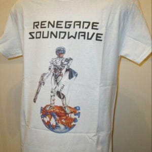 Puede incluir: Camiseta blanca con el texto "RENEGADE SOUNDWAVE" en letras negras. Debajo, un gráfico de una figura futurista con un traje blanco y plateado, sosteniendo un arma, de pie sobre un globo.