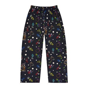 May include: Black pajama pants with a colorful, whimsical pattern. The design features cartoon-like creatures in various colors, including red, yellow, green, and blue, along with white flower accents. The pants have a comfortable, relaxed fit.