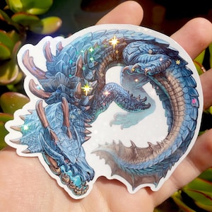 Może przedstawiać: Naklejka przedstawiająca niebieskiego smoka z iryzującymi detalami. Smok ma szczegółowy wzór ze łuskami, pazurami i rogami. Naklejka ma holograficzne wykończenie, z błyszczącymi gwiazdami i motywem fantasy.