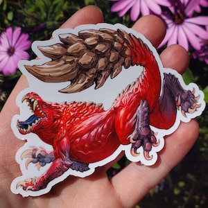 May include: A red and brown monster sticker with a spiky tail and sharp claws. The monster is depicted with an open mouth and a blue tongue.