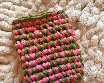Puede incluir: Un estuche rectangular elaborado con tiras de tela gruesas y entrelazadas en tonos alternos de verde oliva y rosa brillante. La estructura de ganchillo presenta un patrón de puntos denso y uniforme en toda la superficie.