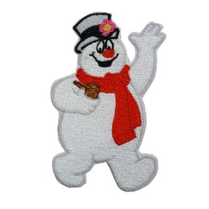 May include: Embroidered patch of a cheerful snowman wearing a black top hat with a pink flower, a red scarf, and holding a brown stick. The snowman has a carrot nose and a smiling face. The patch is white with a stitched border.