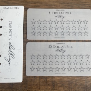May include: A set of Star Notes challenge cards. The cards are light gray with black text and star graphics. One card is a planner insert with holes. The other two cards are for $1 and $2 dollar bill challenges.
