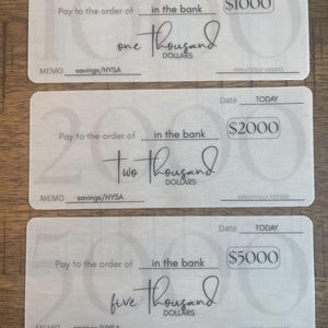 Puede incluir: Tres cheques de fantasía con diferentes cantidades: $1000, $2000 y $5000. Cada cheque presenta las palabras "Pay to the order of", "in the bank" y "savings/HYSA" en la sección de memo. Los cheques son de color claro con una fuente manuscrita.