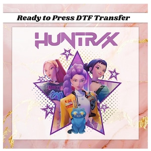 May include: A DTF transfer featuring the word "HUNTRX" in purple, with three stylized female figures inside a purple star. A blue cartoon cat is in the foreground. The text "Ready to Press DTF Transfer" is at the top.
