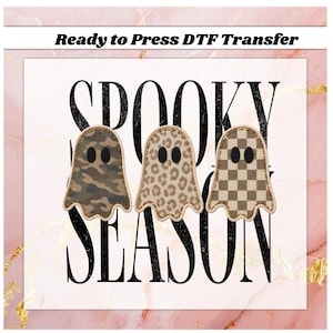 May include: A Ready to Press DTF Transfer featuring three ghost shapes with black oval eyes. The ghosts have camouflage, leopard print, and checkerboard patterns. The background text reads SPOOKY SEASON in large black letters.