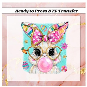 May include: A whimsical illustration of a bunny wearing heart-shaped glasses and blowing a bubblegum bubble. The bunny has a pink polka-dot bow and colorful ears. The image includes the text "Ready to Press DTF Transfer".