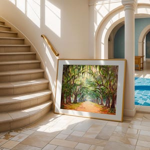 May include: A framed landscape painting of a tree-lined path with sunlight filtering through the branches. The artwork has a gold frame and is leaning against a wall in a bright interior with a staircase and arched doorways.