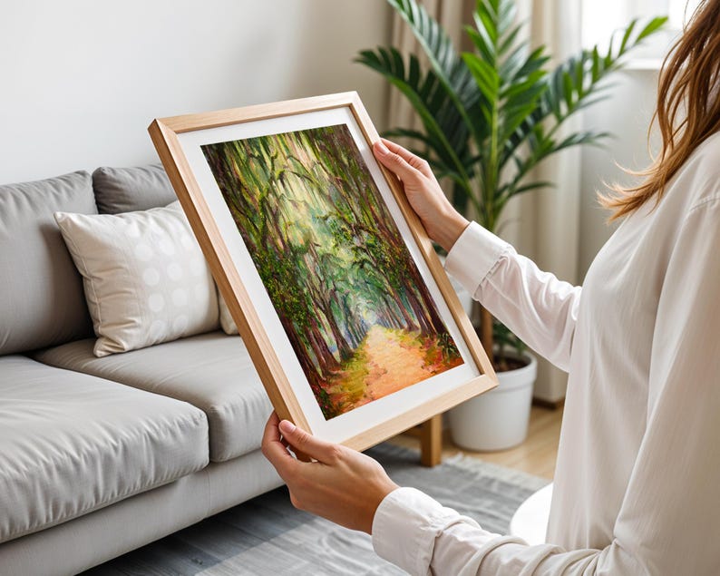 May include: A framed landscape painting showing a path through a forest, with trees lining the sides and sunlight filtering through the leaves. The artwork has a wooden frame and a vibrant colour palette of greens, browns, and oranges.