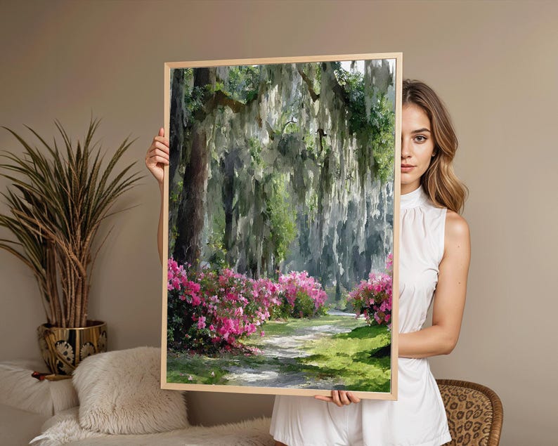 May include: A framed landscape painting depicts a path winding through a lush forest. Pink azaleas line the path, with Spanish moss hanging from the trees. The artwork is in a light wooden frame.