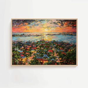 Op de afbeelding: Olieverfschilderij van een stadsgezicht bij zonsondergang, omlijst in licht hout. Het kunstwerk toont een levendige scène met een brug, gebouwen en water onder een kleurrijke lucht met oranje, gele en blauwe tinten.