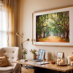May include: A home office featuring a large framed painting of a tree-lined path. A desk with a laptop, candles, and plants sits in front of a cream-coloured chair. A gold desk lamp and beige curtains complete the warm, inviting space.