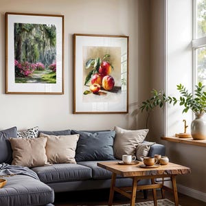 May include: Two framed art prints hang above a gray sectional sofa. One print depicts a path through a lush green and pink floral landscape. The other shows a still life of ripe peaches. A wooden coffee table and decorative items complete the scene.
