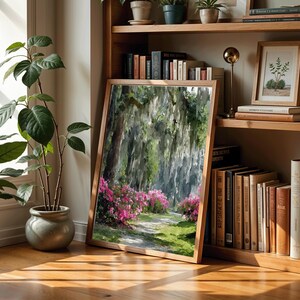 May include: A framed landscape painting of a path through a forest with pink flowers. The painting is leaning against a wooden bookshelf filled with books and small potted plants. The room has hardwood floors and a window.