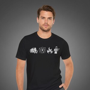 Puede incluir: Camiseta negra con cuatro diseños gráficos blancos: un puño, un átomo, una llama y una calavera con un vaso de precipitados. La camiseta es de manga corta y tiene cuello redondo.