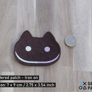 May include: Brown embroidered iron-on patch shaped like a cat with white and pink eyes. The patch is 2.75 inches by 3.54 inches.  Embroidered patch - Iron on. Dimension: 7 x 9 cm / 2.75 x 3.54 inch. X GEEKY PATCHES