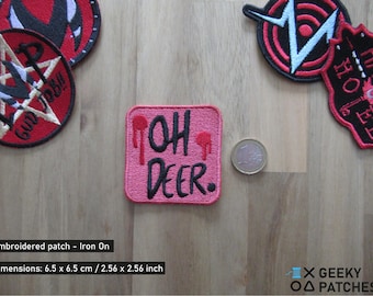 May include: Pink iron-on patch with the text "OH DEER" in black lettering and red dripping paint accents. The patch is 2.56 inches by 2.56 inches.
