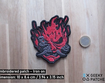 May include: Embroidered iron-on patch featuring a red and black stylized samurai mask with flames. The patch is 3.94 inches by 3.15 inches.