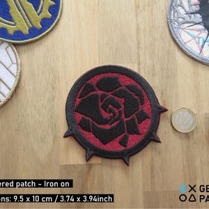 May include: Embroidered iron-on patch featuring a black rose with red accents on a black background. The patch is 3.74 inches by 3.94 inches.