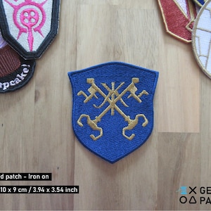 May include: Blue embroidered iron-on patch with a gold design of two crossed keys on a shield. The patch measures 10 cm by 9 cm.