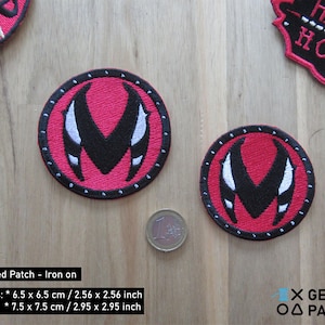 May include: Two round, embroidered patches with a red background, black central design, and white accents. The patches are approximately 2.56 to 2.95 inches in diameter. The patches are iron-on.