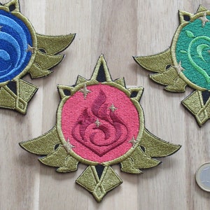 May include: Three embroidered patches with gold accents. Each patch features a different symbol: a blue water symbol, a red fire symbol, and a green heart symbol. Each symbol is surrounded by gold stars.