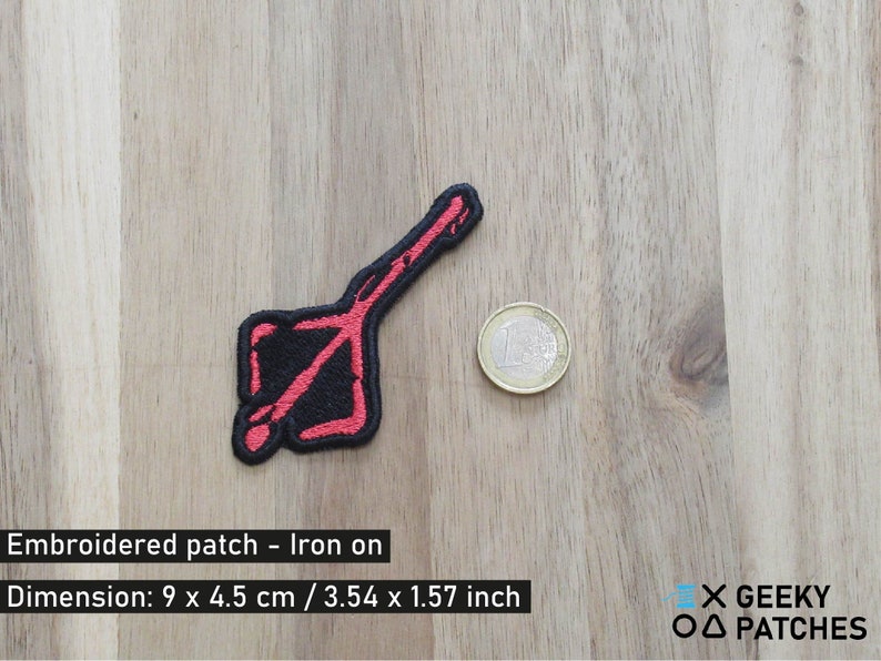 May include: Red embroidered iron-on patch with a black and red design. The patch is 3.54 inches by 1.57 inches.