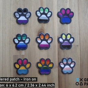 May include: Nine embroidered iron-on patches in the shape of paw prints. Each patch features a different pride flag design, including the asexual, genderqueer, lesbian, bisexual, pansexual, transgender, non-binary, and intersex flags. The patches are 6 x 6.2 cm / 2.36 x 2.44 inches.
