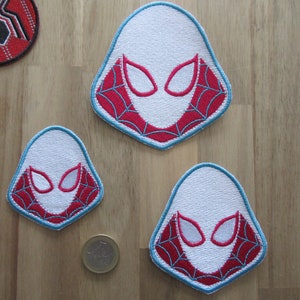 May include: Three embroidered iron-on patches featuring a white spider-man mask with red and blue webbing. The patches are different sizes.