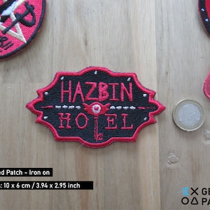 May include: An iron-on embroidered patch featuring a black and red sign with the text "Hazbin Hotel" in white. The sign has a red eye with a keyhole in the centre. The patch is 3.94 inches by 2.95 inches.