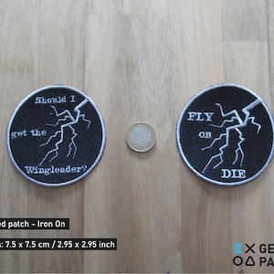 Può includere: Due toppe rotonde nere ricamate con testo bianco e un disegno a forma di fulmine. Una toppa recita "Should I get the Wingleader?" e l'altra "Fly or Die". Ogni toppa misura 7,5 cm di diametro.