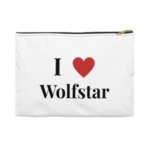 May include: A white rectangular zippered pouch featuring the black text I and Wolfstar with a red heart symbol positioned between the words. The pouch has a black zipper closure at the top and a gold-toned metal zipper pull tab on the right side.