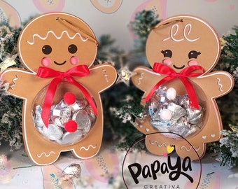Peut inclure: Deux décorations en forme de bonhomme en pain d'épices avec des fenêtres en plastique transparent remplies de bonbons argentés. Les décorations sont sur un fond rose avec un motif de papaye. Le texte "Papaya Creativa" est en bas de l'image. Des icônes de médias sociaux sont sur le côté droit de l'image avec le texte "@papayacreativa".