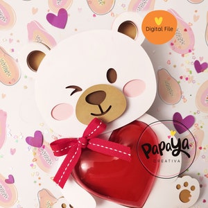 May include: A white papercraft bear holding a red heart with a pink and white ribbon. The bear has a brown nose and brown eyes. The background is pink with a pattern of papaya fruit.