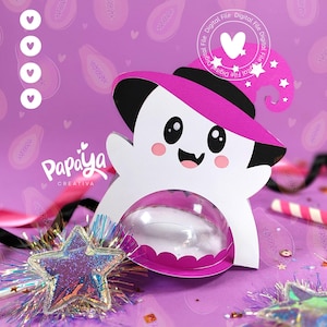 May include: A white ghost wearing a pink witch hat with a black brim and a black star on the hat. The ghost has a pink mouth and pink cheeks. The ghost is holding a pink and white candy jar. The background is purple with pink papaya fruit designs. The text "Papaya Creativa" is in the lower left corner of the image.