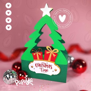 May include: A green Christmas tree-shaped gift box with a white star on top. The box features two red gift boxes with gold bows and the text "Christmas Time". Decorative red and silver ornaments are scattered around the box.