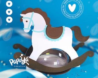 May include: A white rocking horse with a brown saddle and blue trim. The horse is on a brown base with a clear plastic dome. The background is blue with white hearts and papaya designs. The text "Papaya Creativa" is at the bottom of the image.