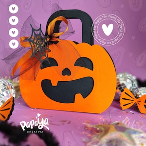 Puede incluir: Una caja con forma de calabaza de papel naranja con un asa negra y recortes de cara. Una telaraña y un lazo negros adornan la parte superior. El texto "Digital File" y un corazón están en el lado derecho.
