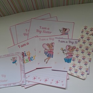 Könnte beinhalten: Eine Sammlung von rosa und weißen Karten und Schreibwaren mit dem Text "I am a Big Sister". Die Karten zeigen Illustrationen einer Fee mit einem Zauberstab und einem herzförmigen Ballon. Einige Karten haben einen rosa Rand.