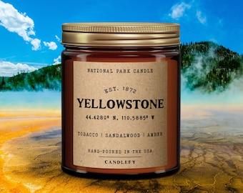 May include: A brown glass candle jar with a gold lid. The label reads "National Park Candle", "Est. 1872", "Yellowstone", "44.4280° N, 110.5885° W", "Tobacco | Sandalwood | Amber", "Hand-poured in the USA", and "Candlefy".
